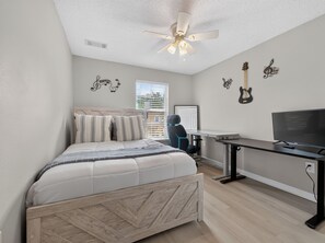 A bedroom with a bed, a desk, a television, and wall decorations including musical notes and a guitar. - PROMO: 3BR Family Villa with Resort Amenities! - by Blue Sky Villas (Kissimmee)