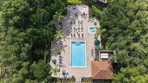 Vista aèria d'un complex turístic amb piscina, gandules i una zona de terrassa coberta envoltada de vegetació densa.