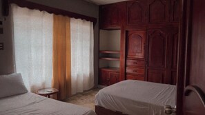 Ein Schlafzimmer mit zwei Betten, einem Holzschrank und einem kleinen runden Tisch.