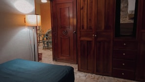 A bedroom with a bed, a wooden wardrobe, and a lamp.