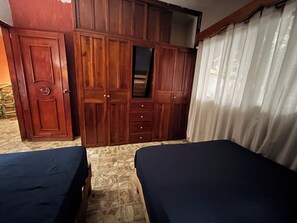 Ein Zimmer mit Holzschrank, Bett und Vorhang.