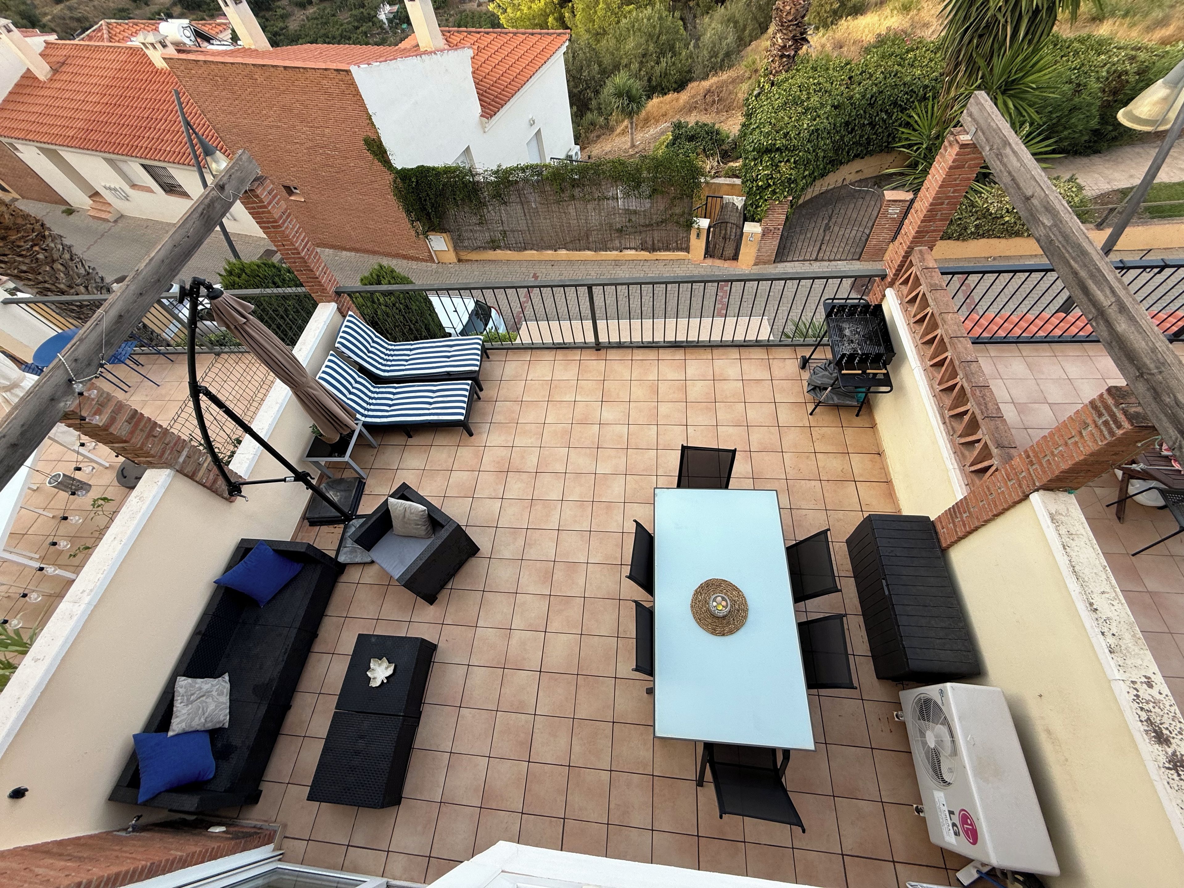 A rooftop terrace with a table, chairs, and lounge seating.