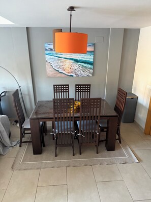 A dining area with a table and chairs, a hanging light fixture, and a wall-mounted painting. - House with ocean views and a year-round pool in Almuñécar (Almuñécar)