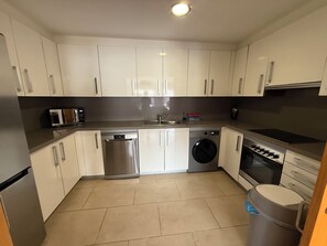 A modern kitchen with white cabinets, stainless steel appliances, and a tiled floor. - House with ocean views and a year-round pool in Almuñécar (Almuñécar)