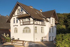 Un bâtiment à deux étages de style architectural traditionnel, doté d’un balcon à l’étage supérieur et d’une entrée bien visible.