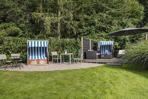 An outdoor seating area with striped lounge chairs, a small table, and an umbrella. - Holiday apartment with 1 bedroom (Travemünde)