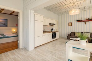 A modern kitchen with white cabinetry, a wooden countertop, and a hanging light fixture. - Holiday apartment with 1 bedroom (Travemünde)