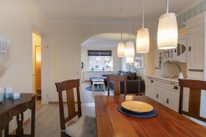 A dining area with a wooden table, chairs, and pendant lights. - Holiday apartment with 1 bedroom (Travemünde)