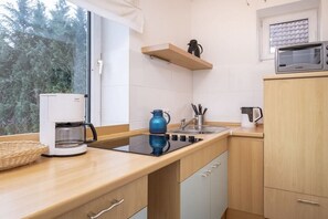 A modern kitchen with a built-in stove, a coffee maker, a kettle, and a microwave on the countertop. - Holiday apartment with 1 bedroom (Travemünde)