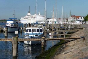 A marina with boats docked, a cruise ship in the background, and a wooden pier. - Holiday apartment with 1 bedroom (Travemünde)