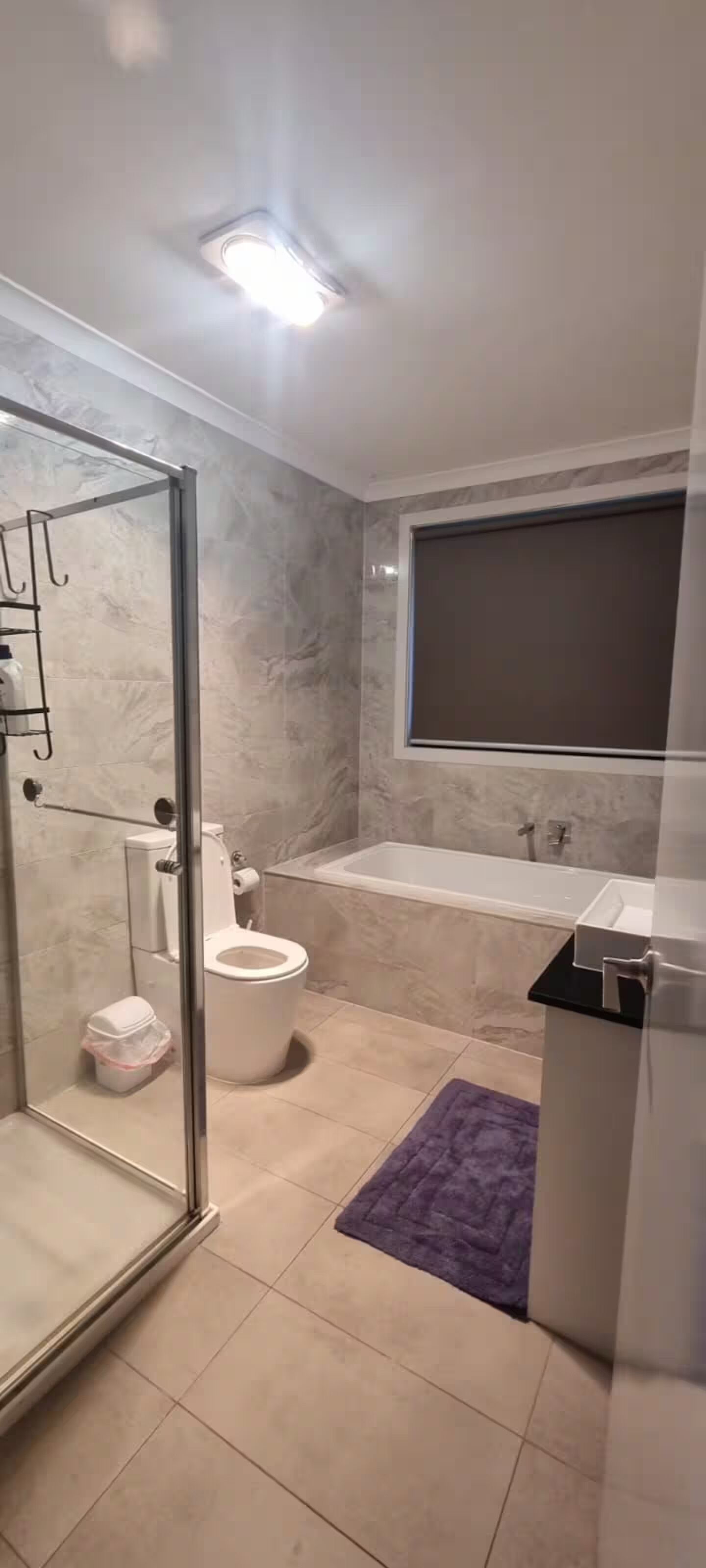 Un baño moderno con ducha envuelta en vidrio, inodoro, bañera y lavamanos.