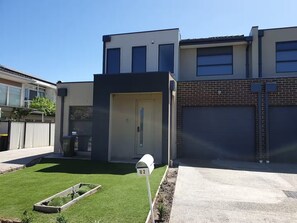 Un edificio residencial moderno con garaje, césped bien cuidado y buzón.