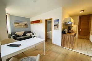 Ein modernes Wohnzimmer mit einer Couch, einem Esstisch und einer Küchenzeile mit einer Holzausstattung.