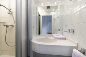 A modern bathroom with a glass shower enclosure, a white sink, and a mirror. - Holiday apartment with 2 bedrooms (Travemünde)
