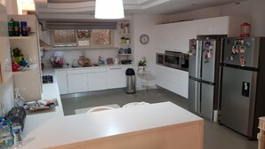 Una cocina moderna con gabinetes blancos, electrodomésticos de acero inoxidable y una isla central con asientos.