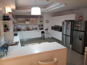 Una cucina moderna con mobili bianchi, elettrodomestici in acciaio inossidabile e un'isola centrale con posti a sedere.