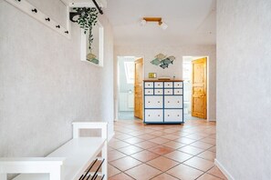 Un pasillo con un banco blanco, un armario de madera con cajones y un piso de baldosas.
