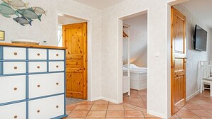 Quarto com guarda-roupa de madeira, uma cama e televisão na parede.