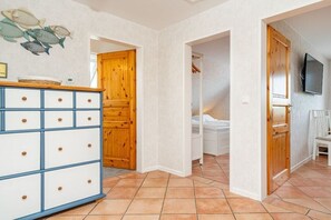 Une pièce comprenant une armoire en bois, un lit et un téléviseur fixé au mur.