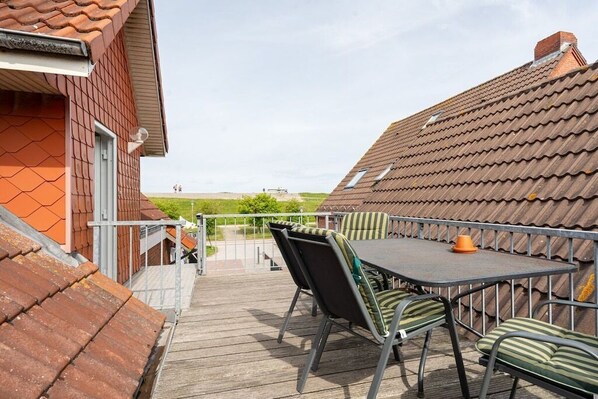 Une terrasse avec une table et des chaises, donnant sur un champ verdoyant.
