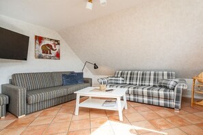A living room with two striped sofas, a white coffee table, and a painting of an elephant. - Holiday apartment with 1 bedroom (Norden-Norddeich)