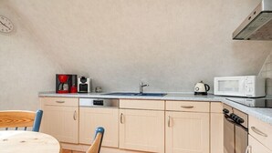 Een kleine keuken met een spoelbak, magnetron en kookplaat.