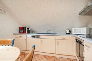 A compact kitchen with a sink, microwave, and stove. - Holiday apartment with 1 bedroom (Norden-Norddeich)
