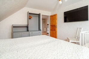 A bedroom with a bed, a wardrobe, a television, and a crib. - Holiday apartment with 1 bedroom (Norden-Norddeich)