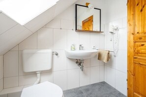 Une petite salle de bain avec des toilettes, un lavabo et un miroir.