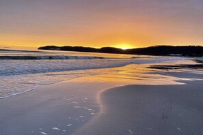 A beach with a sunset, waves, and a distant landmass. - 621 in the Strandvilla Seeadler (Ostseebad Binz)