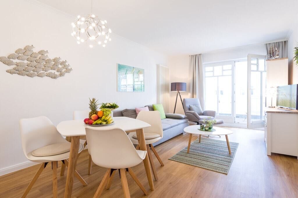 Ein modernes Wohnzimmer mit Essbereich, einer Couch, einem Couchtisch und einer Chandelüstere.
