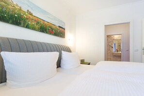 A hotel room with a bed, a headboard, a painting on the wall, and a bathroom visible through an open door. - 621 in the Strandvilla Seeadler (Ostseebad Binz)