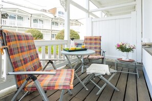 Un espace extérieur abrité, aménagé avec une table, des chaises et une petite table sur laquelle est posée une plante.