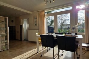 A dining area with a table and chairs, a window with curtains, and a view of the outdoors. - Bungalow with 2 bedrooms (Oostkapelle)
