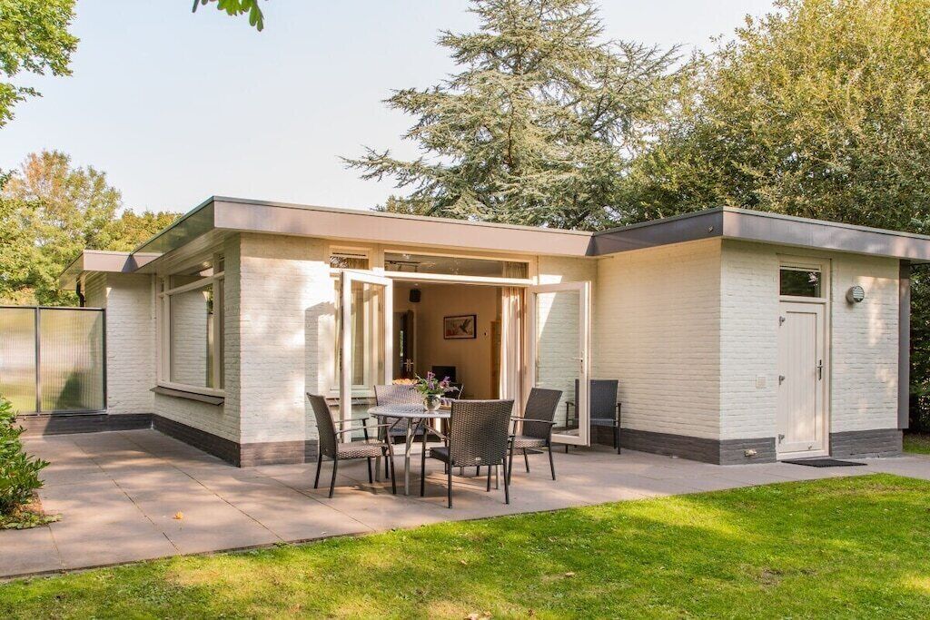 Een modern huis met een patio, inclusief een tafel en stoelen.
