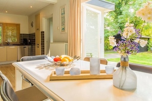 Een moderne keuken met een eethoek, een fruitschaal en een vaas met bloemen op tafel.