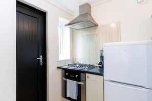 A compact kitchen with a gas stove, oven, and a white refrigerator. - Spacious 2BR Home | Attic Room, Parking & WiFi (Sunderland)