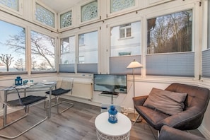A modern interior with a dining area, a sofa, and a TV. - Holiday apartment with 1 bedroom (Ostseebad Binz)