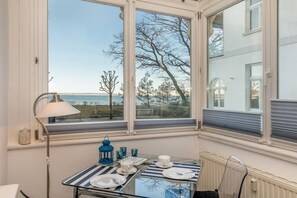 Een eettafel voor twee, met uitzicht op zee en bomen.