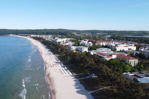 Un paysage urbain côtier avec une plage, des bâtiments et une zone boisée.
