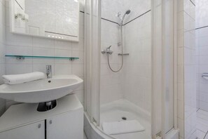 Une salle de bain moderne avec un lavabo blanc, un miroir et une douche.