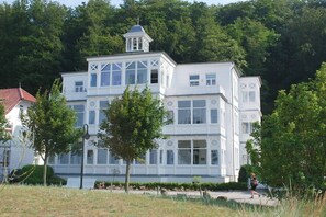 Un bâtiment blanc doté d’une tour, de grandes fenêtres et d’un balcon.