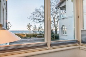 A room with a large window overlooking a beach and a building. - Holiday apartment with 1 bedroom (Ostseebad Binz)