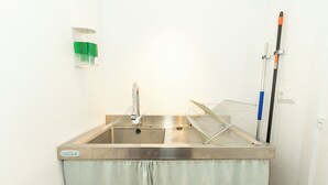 A stainless steel sink with a towel rack and a mop on the wall.