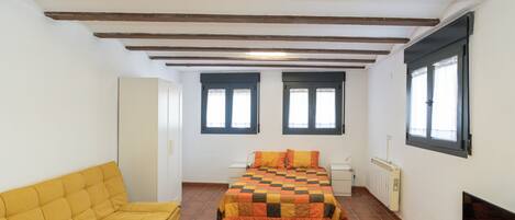 Een kamer met een bed, een bank, een televisie en een raam.