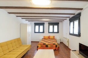 Una habitación con cama, sofá, televisión y ventana.