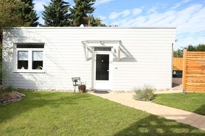 A single-story white building with a front door, a small window, and a doorbell. - Bungalow in Travemünde with swimming pool (Travemünde)