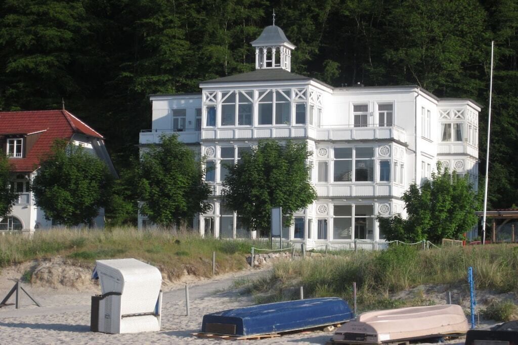 Ein weißes Gebäude mit einem Turm, umgeben von Bäumen und einem Strand.