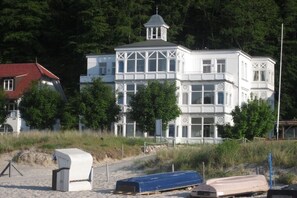 A white building with a tower, surrounded by trees and a beach. - Vista Mare at Villa Agnes (Binz)