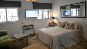 Una camera da letto con un letto, una TV, una scrivania, una sedia e una lampada.